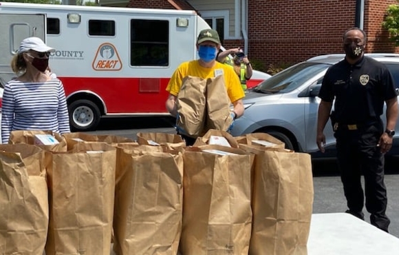 Volunteers holding brown paper bags of groceries